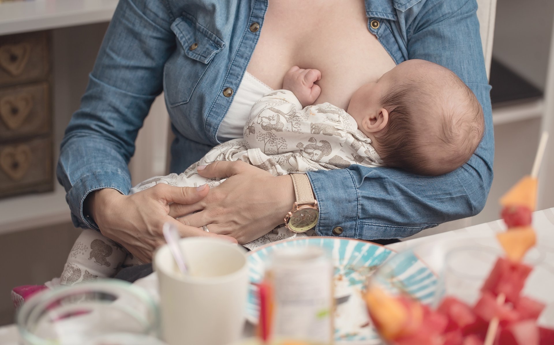 Mama siedzi przy stole i karmi dziecko piersia